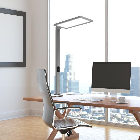 A rectangular-head desk lamp beside a computer workstation by a window